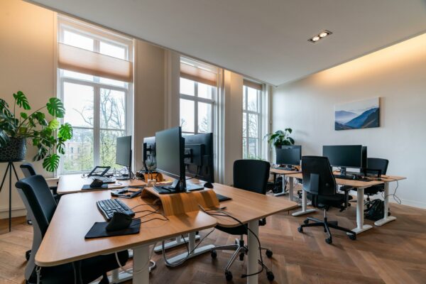 Modern kantoor met meerdere werkplekken, grote ramen en uitzicht op de Lange Vijverberg in Den Haag.